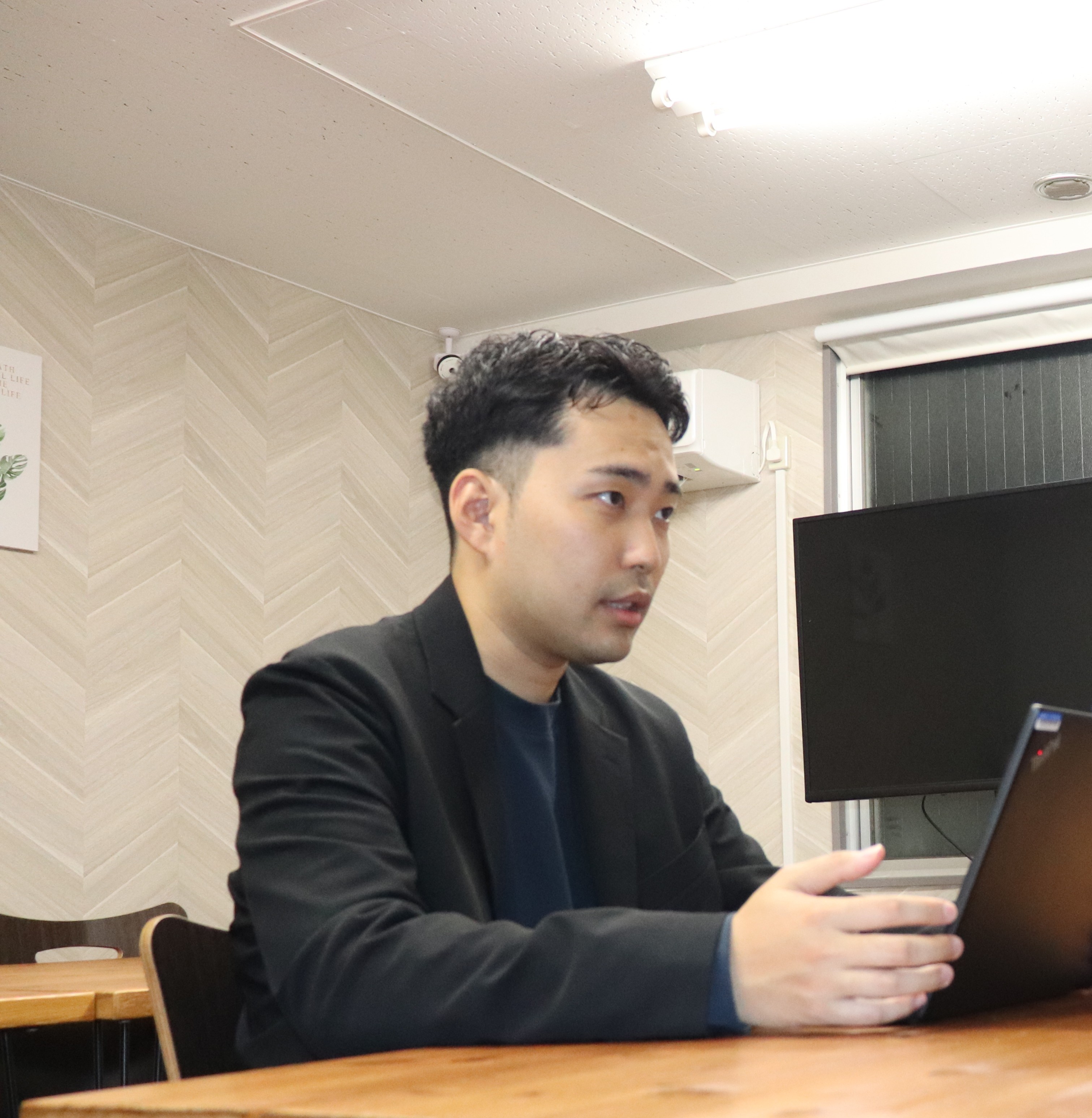 オフィスのデスクでノートPCに向かい、モニターを見ながら打ち合わせをする株式会社Luffのメンバー